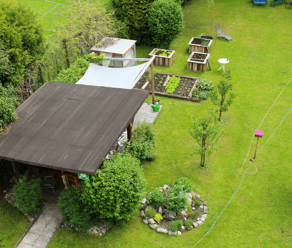 Unser großzügiger Garten mit Hochbeeten und Obstbäumen bietet eine gemütliche Aufenthaltsmöglichkeit im Freien.