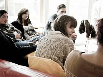 Jugendliche sitzen auf Sofas und sprechen miteinander.