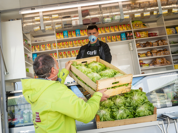 Krauthaeupl-Bauer übergibt Salatspende an Caritas-Mitarbeiter für die Lebensmittelnotausgabe